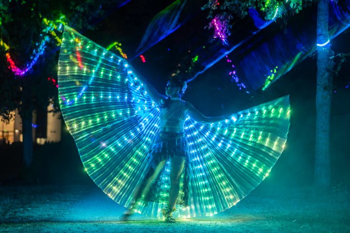 Lichtdanseres met kleurrijke LED-vleugels onder de lasers