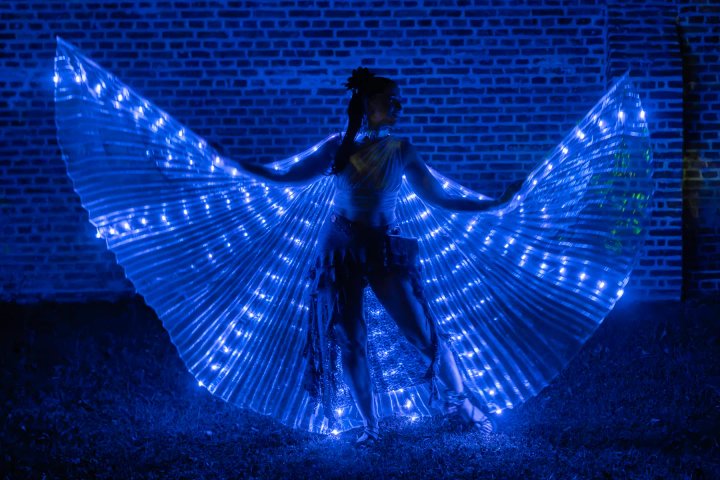 Lichtdanseres met LED-vleugels voor een historische muur