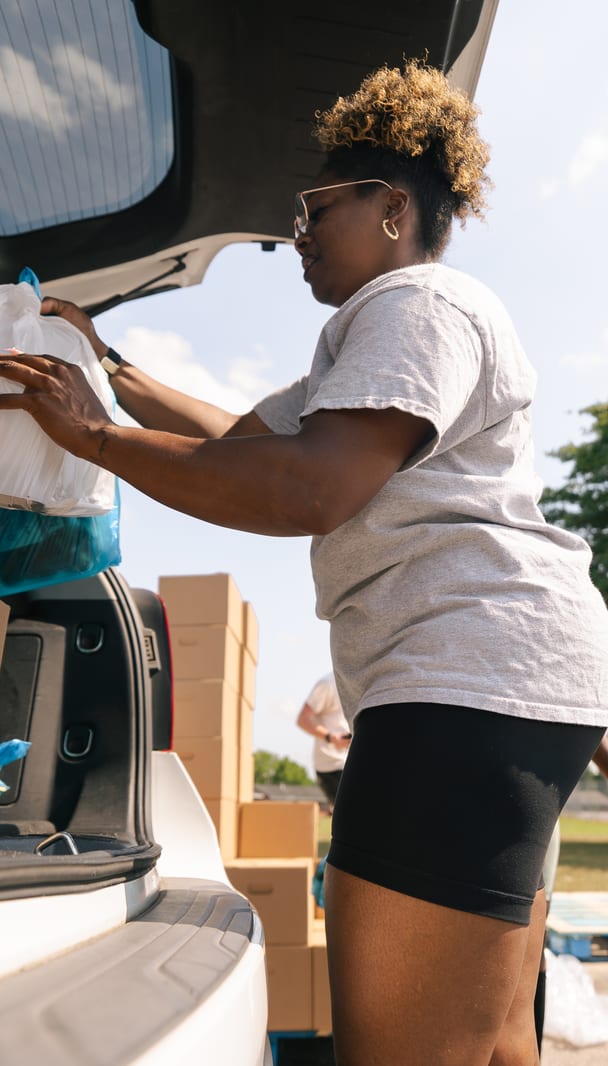 A volunteer loading a box into a trunk
