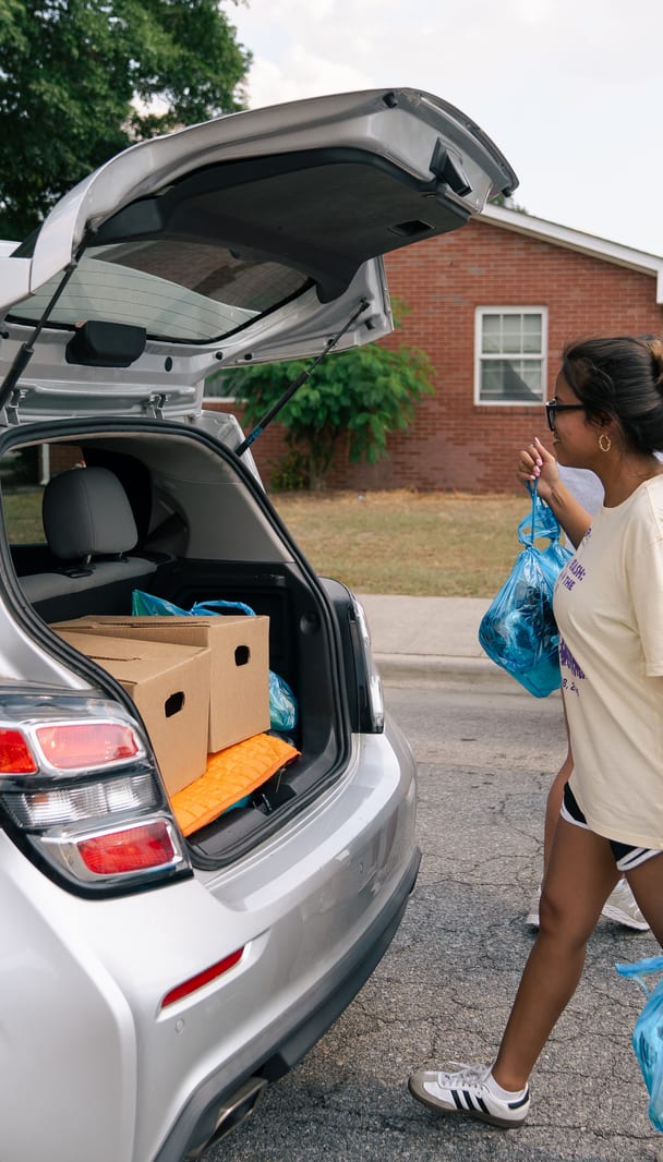 Volunteers beside a car loaded with groceries