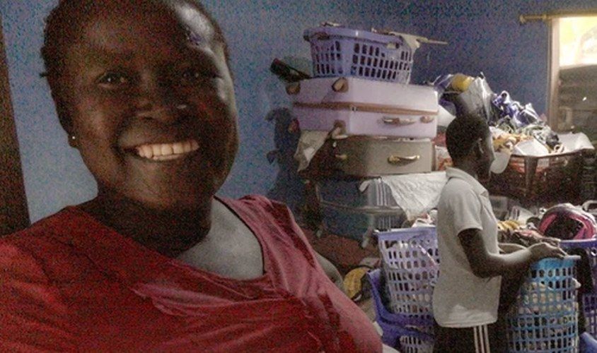 Hannah smiling beside stacked baskets in her community