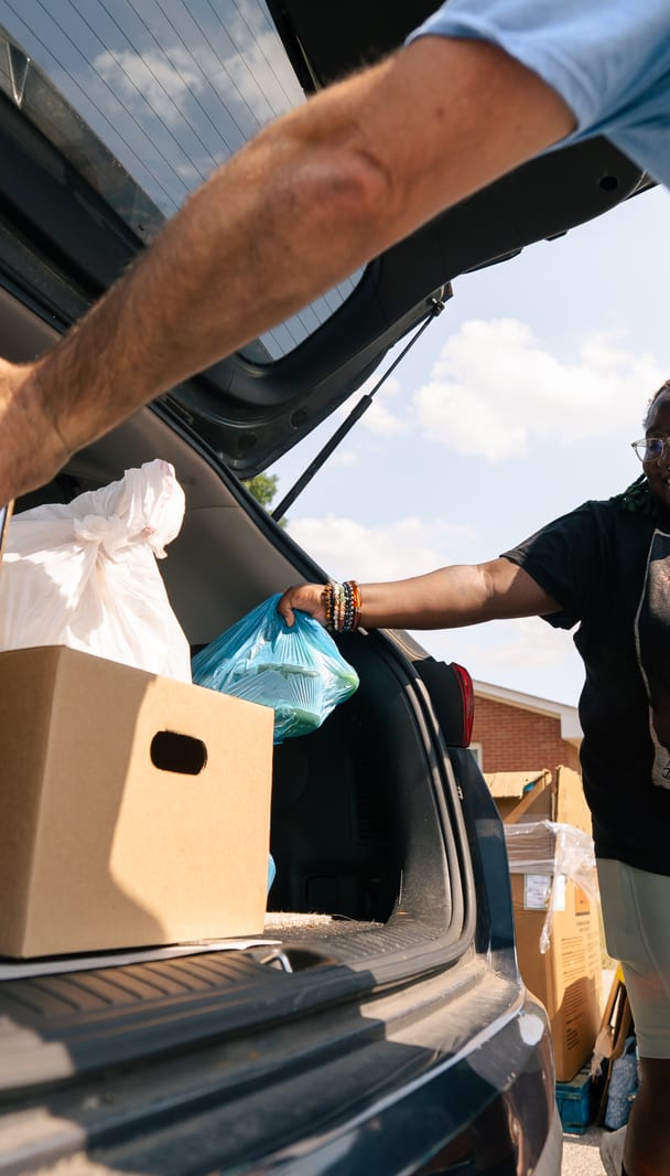 Hands placing a box of food into a trunk