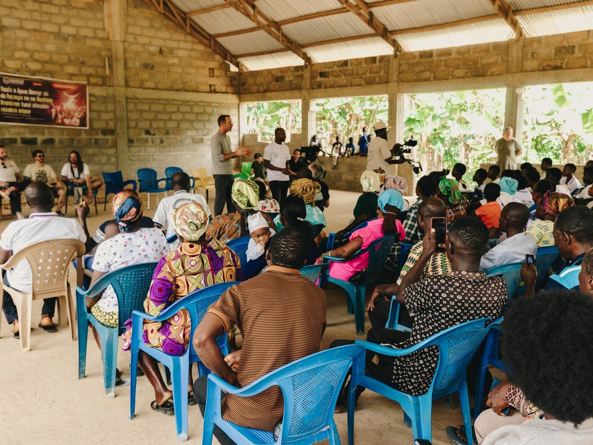 Families seated together at a community meeting in a Ghanaian cocoa-growing village