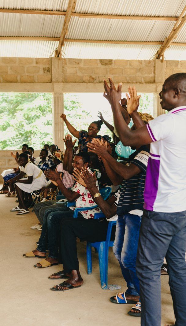 A community leader addressing families seated under the pavilion