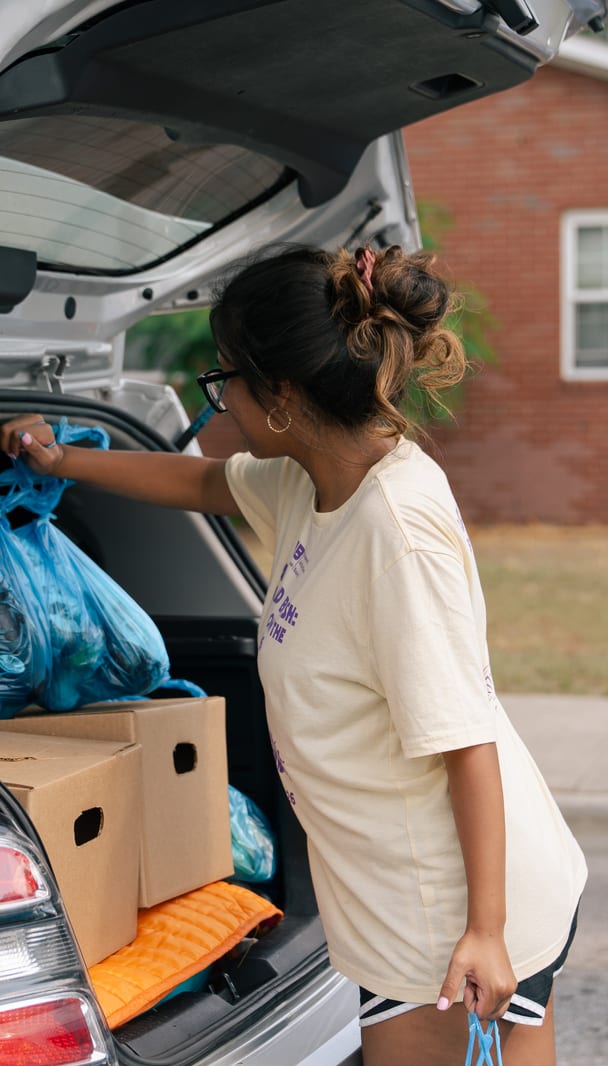 A volunteer loading bags into a trunk