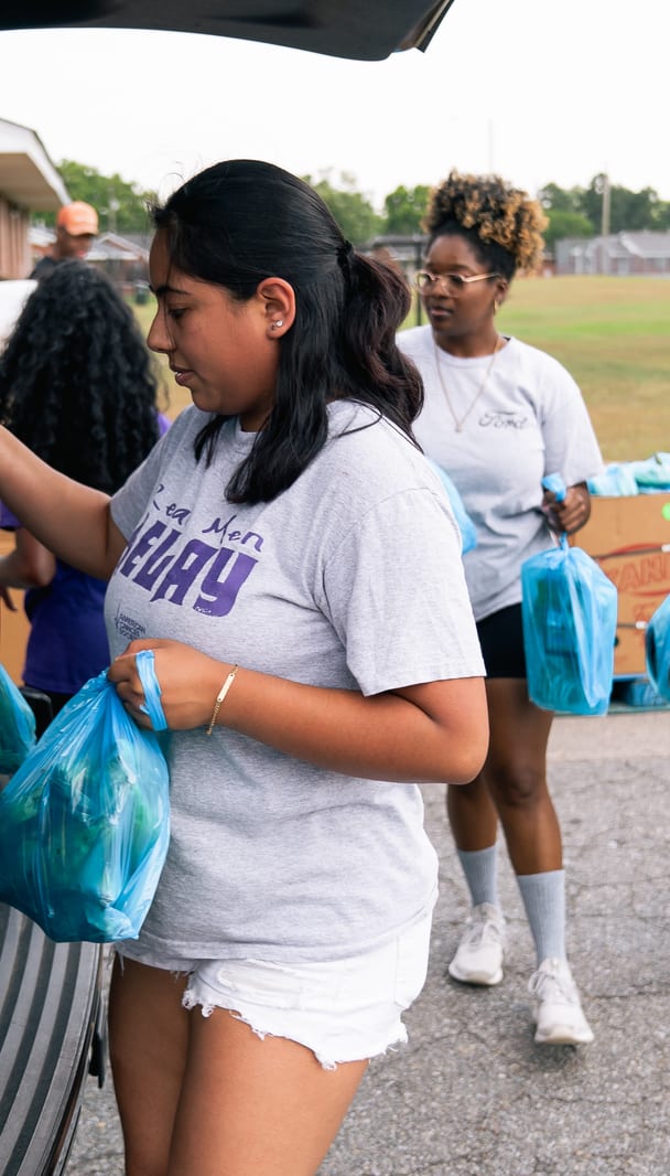 Volunteers carrying groceries across the lot