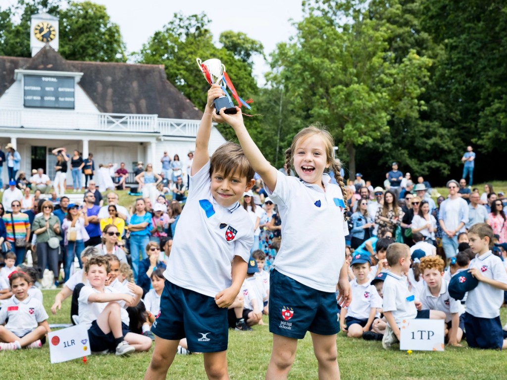 Image of people outside with a close up of two pupils holding up a small trophy together