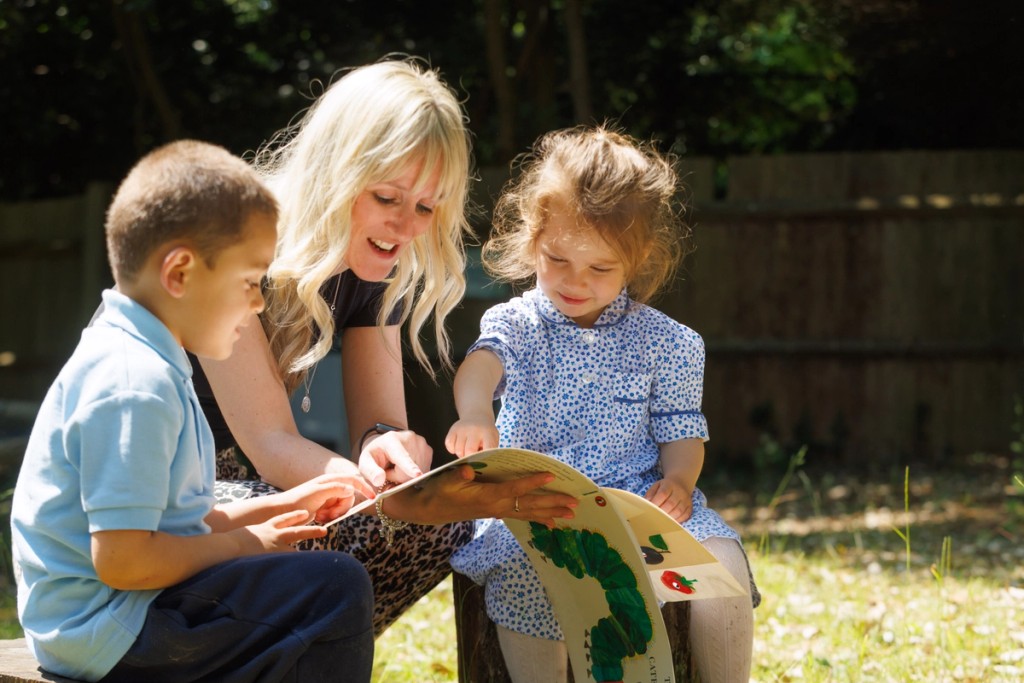 Image of a woman in between two children holding a book 