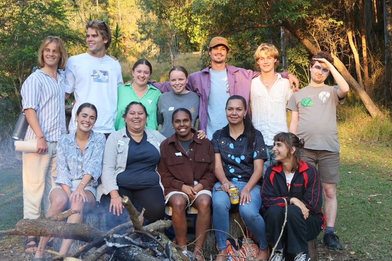 Smiling young people around a campfire.