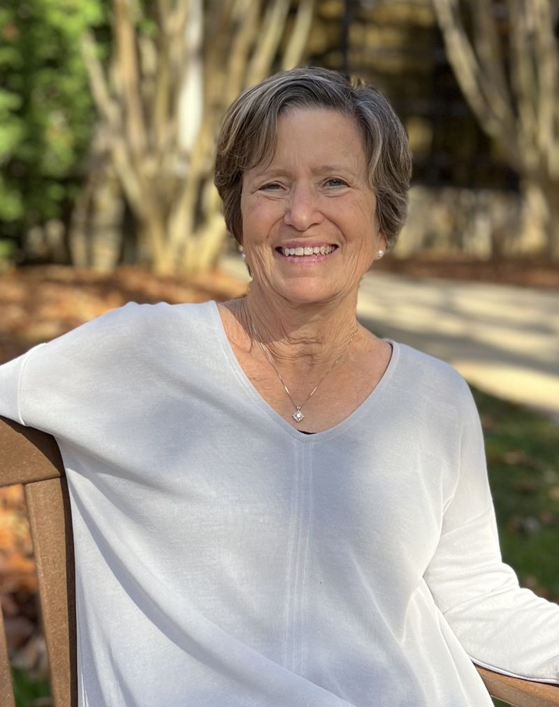 Lynn sitting on a bench in the sun smiling