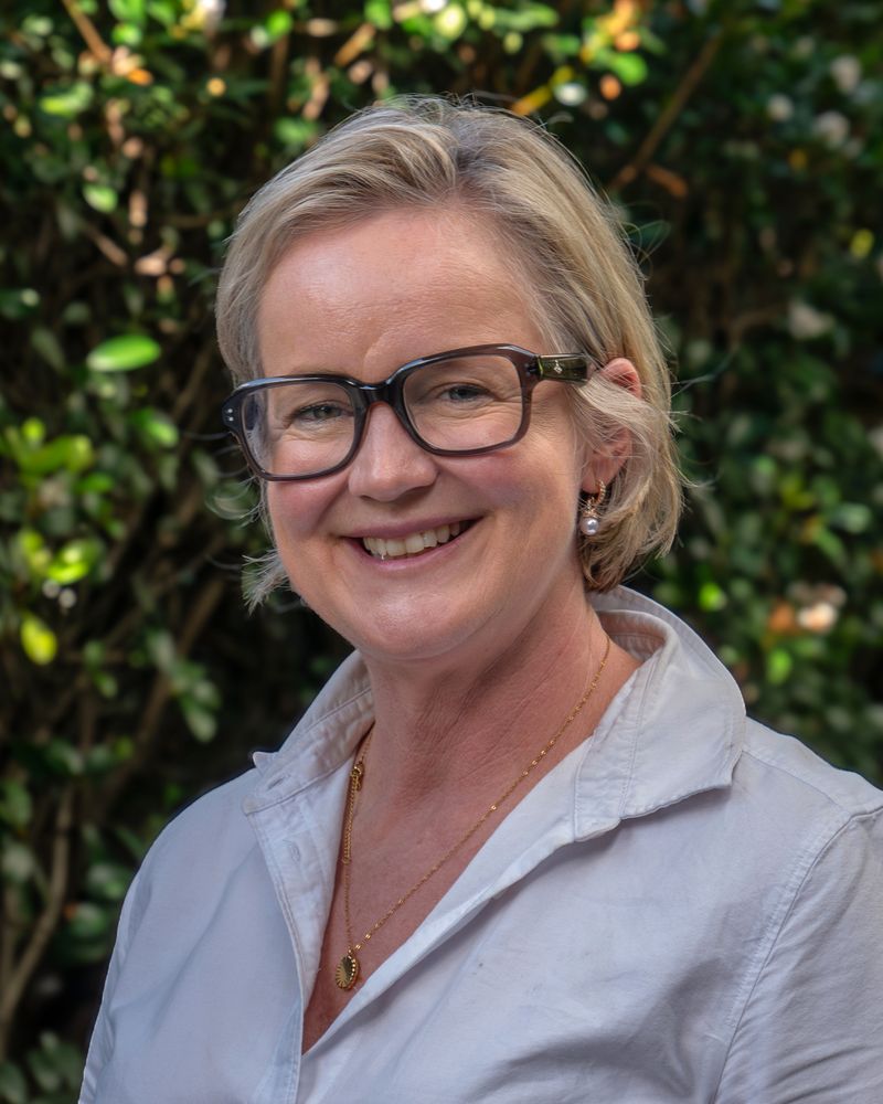 Jac smiling with glasses and an open knecked shirt