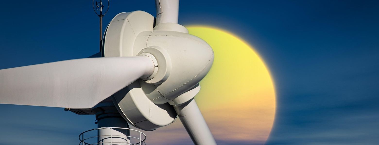 The nacelle and blades of a wind turbine against a large setting sun