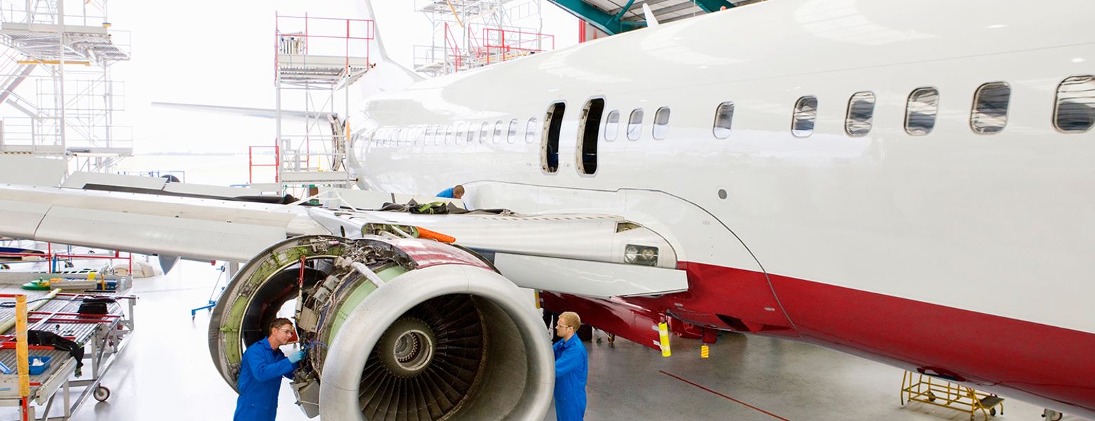 Two engineers inspecting a jet engine on an aircraft in a hangar