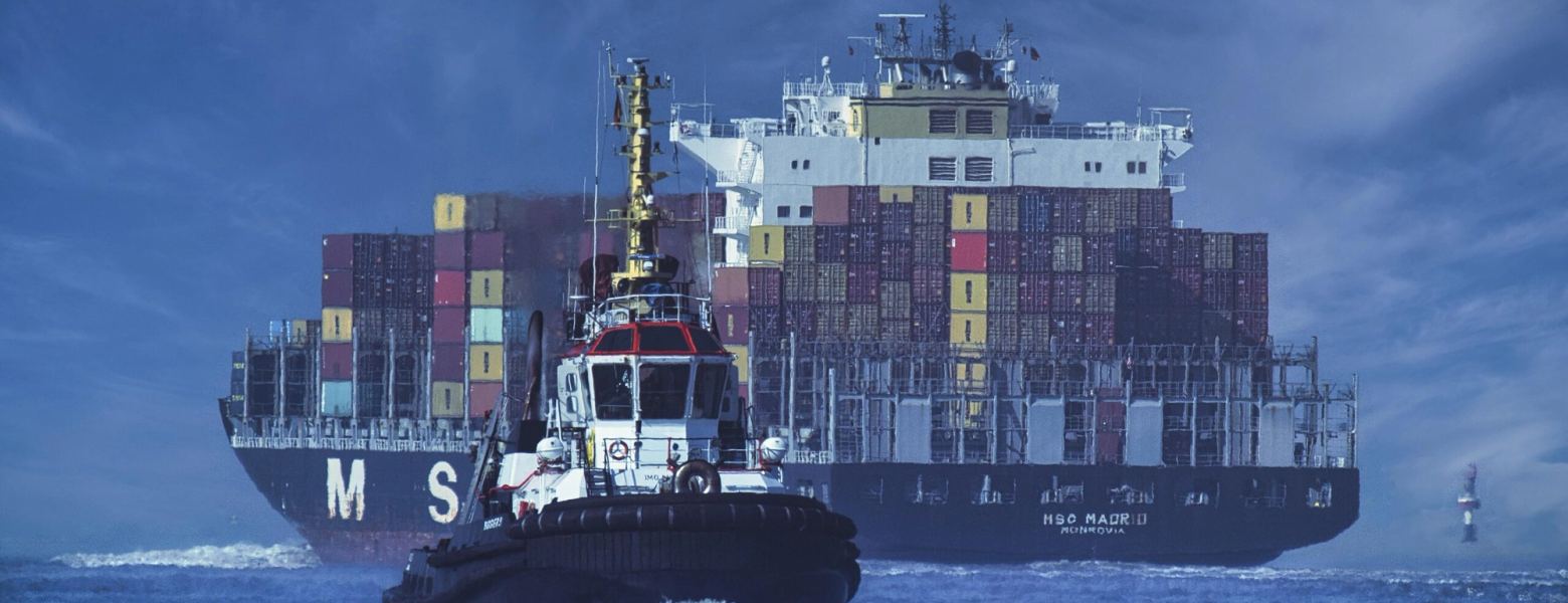 A tug working alongside a loaded container ship