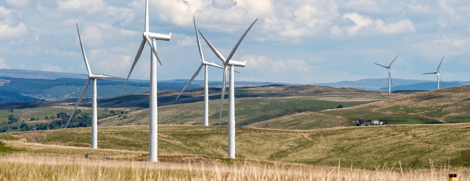Wind turbines on rolling grassland under a partly cloudy sky