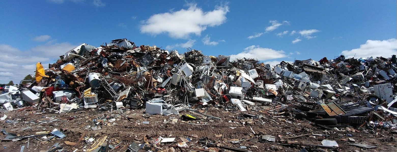 A heap of scrap metal and industrial waste under a blue sky
