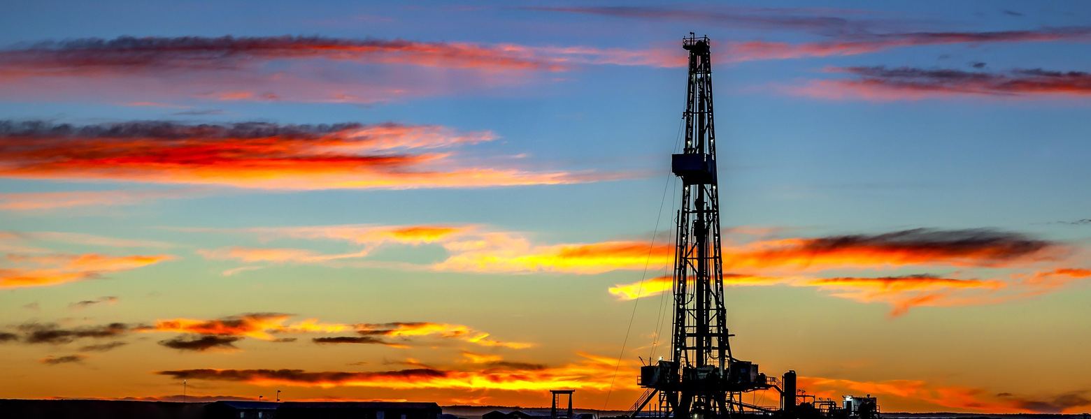 A drilling rig silhouetted against a red sunset