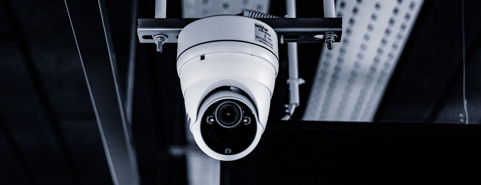 A white dome security camera mounted on an industrial ceiling