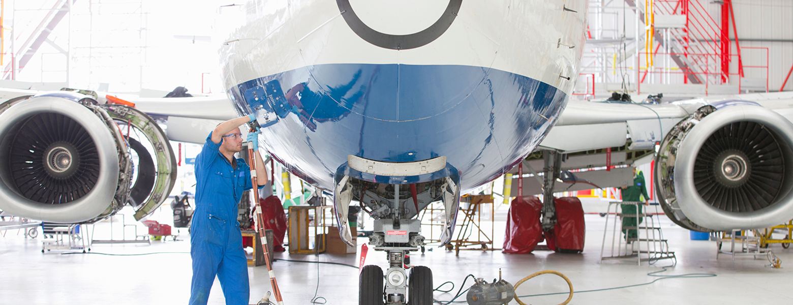 An engineer working beneath the nose of an airliner in a hangar