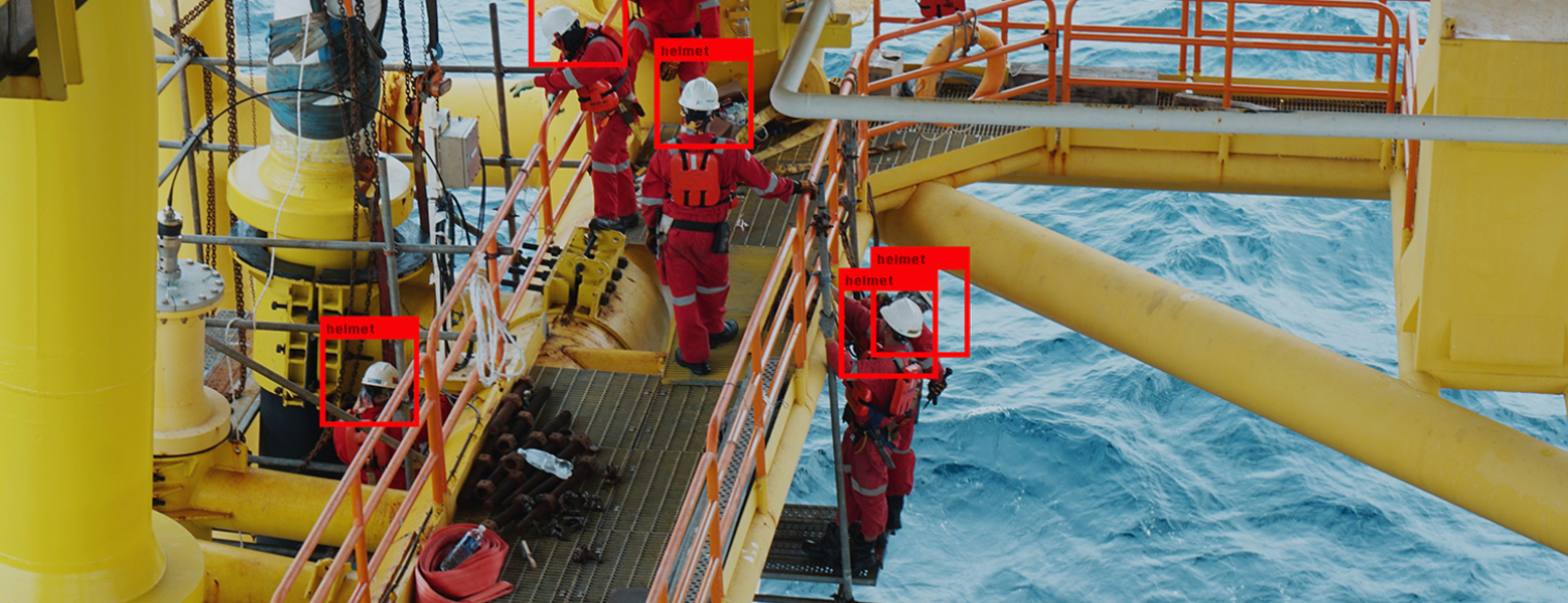 Workers in red overalls on the deck of an offshore platform above open sea