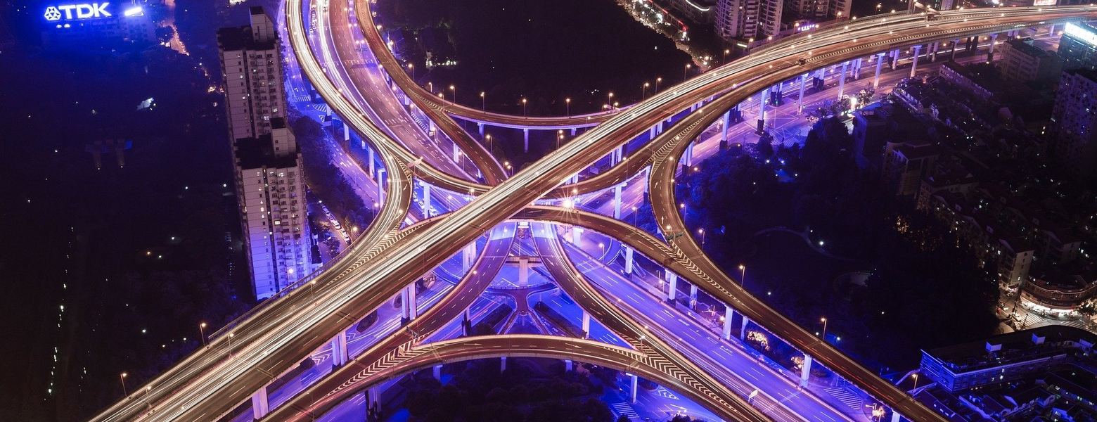 A multi-level highway interchange lit up at night in a dense city