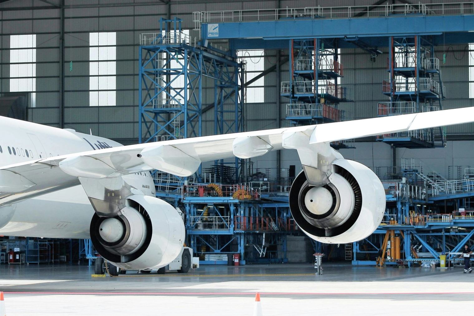 Aircraft in a maintenance hangar with scaffolding around the wing and engines