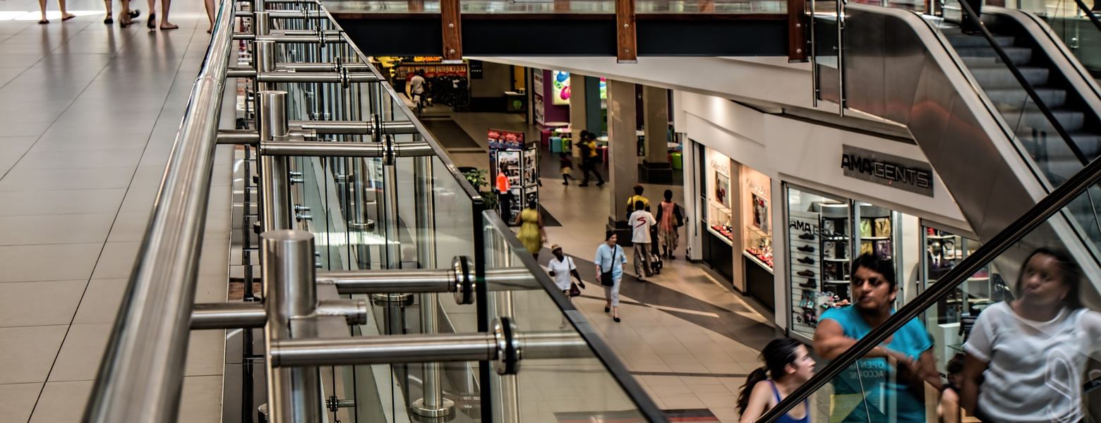 Shoppers on escalators inside a multi-level shopping mall