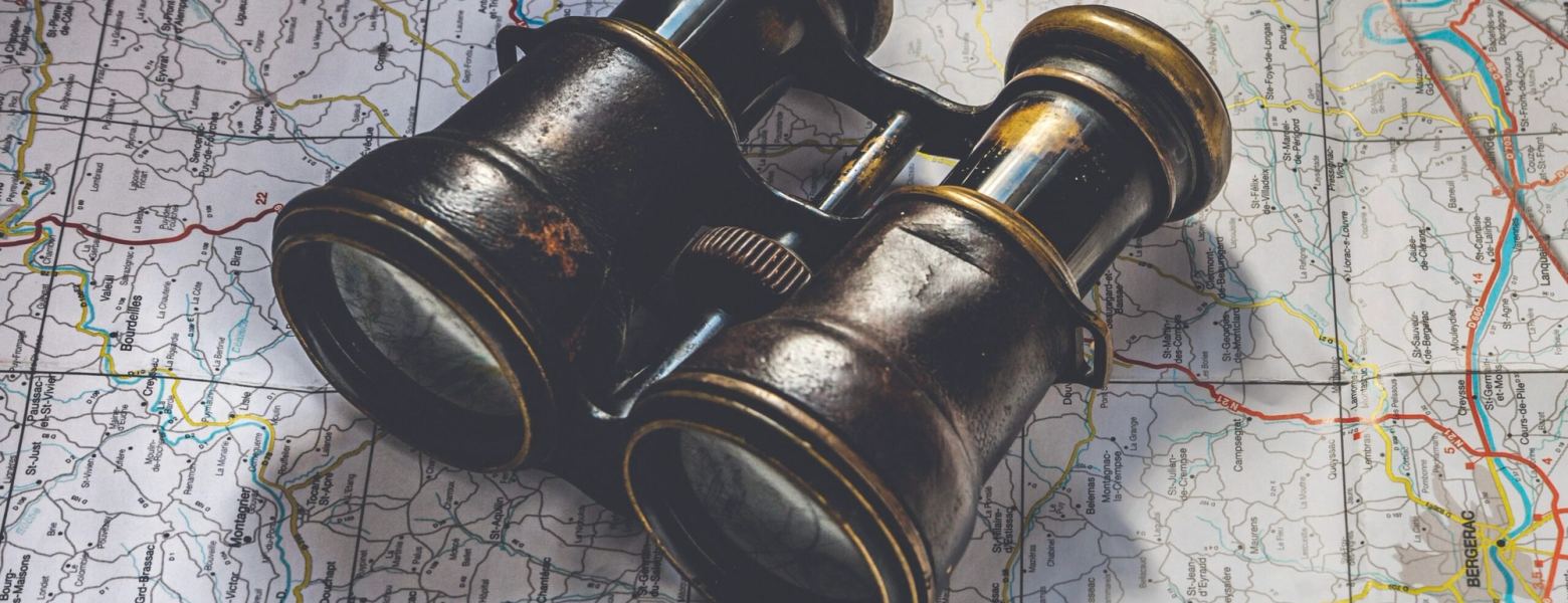 A pair of brass binoculars resting on a folded road map
