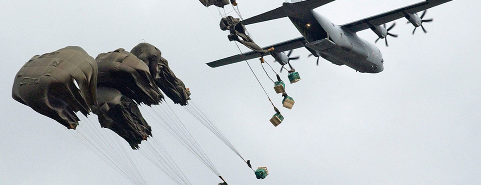 A military transport aircraft air-dropping supply pallets by parachute