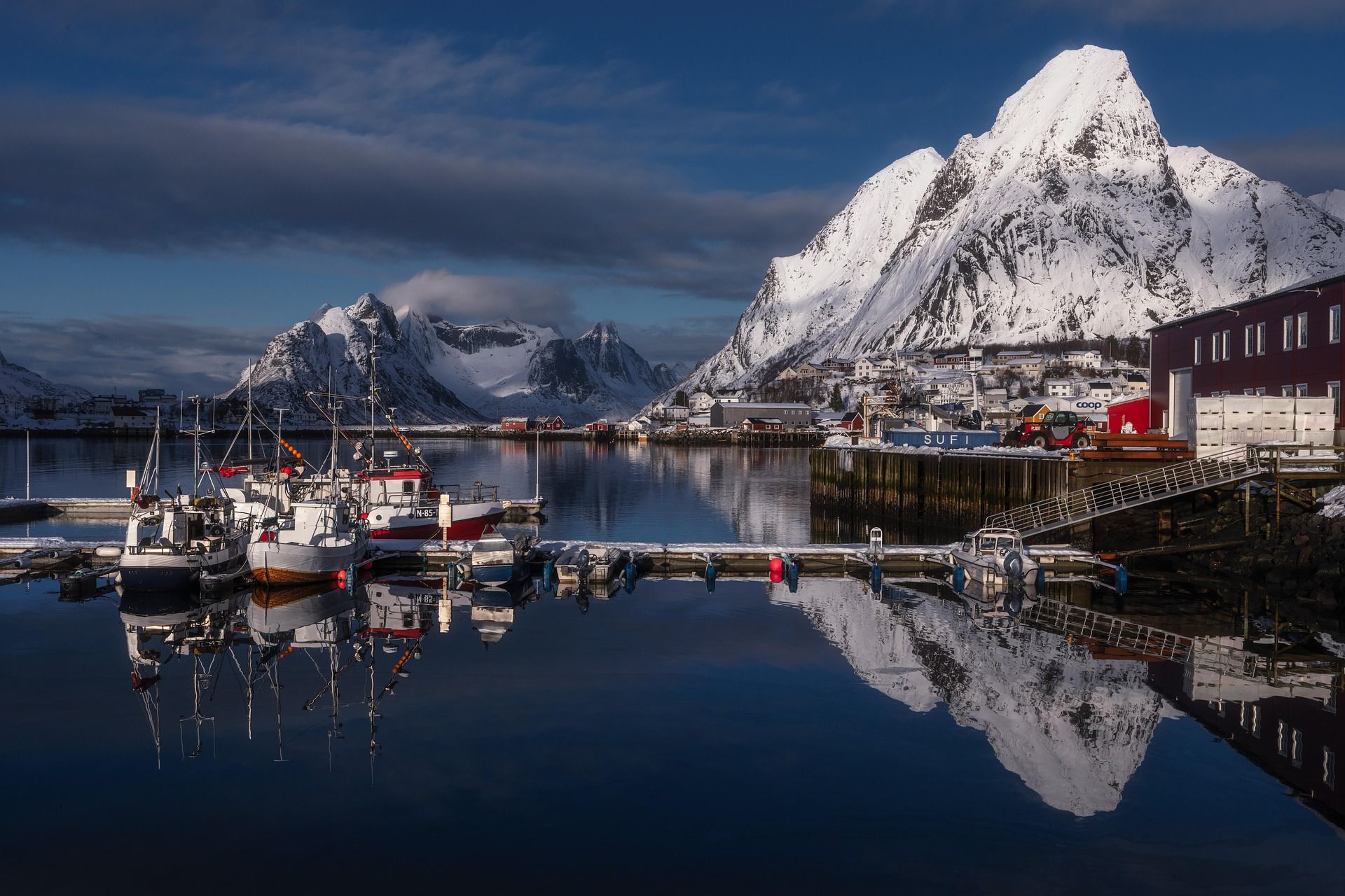 Bilde fra en kai i lofoten med båter og fjell i bakgrunnen.