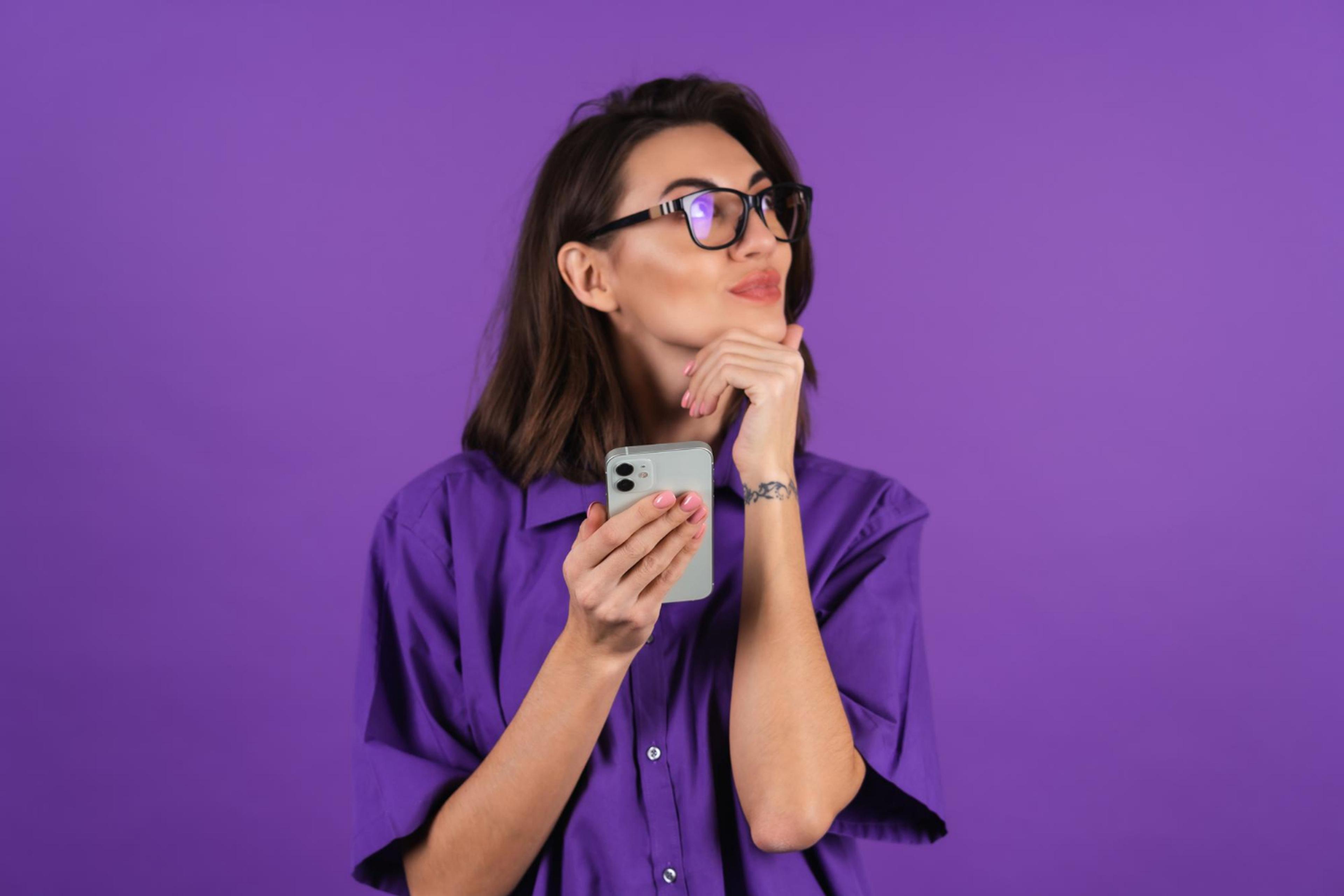Nysgjerrig kvinne som holder en telefon. Lilla bakgrunn