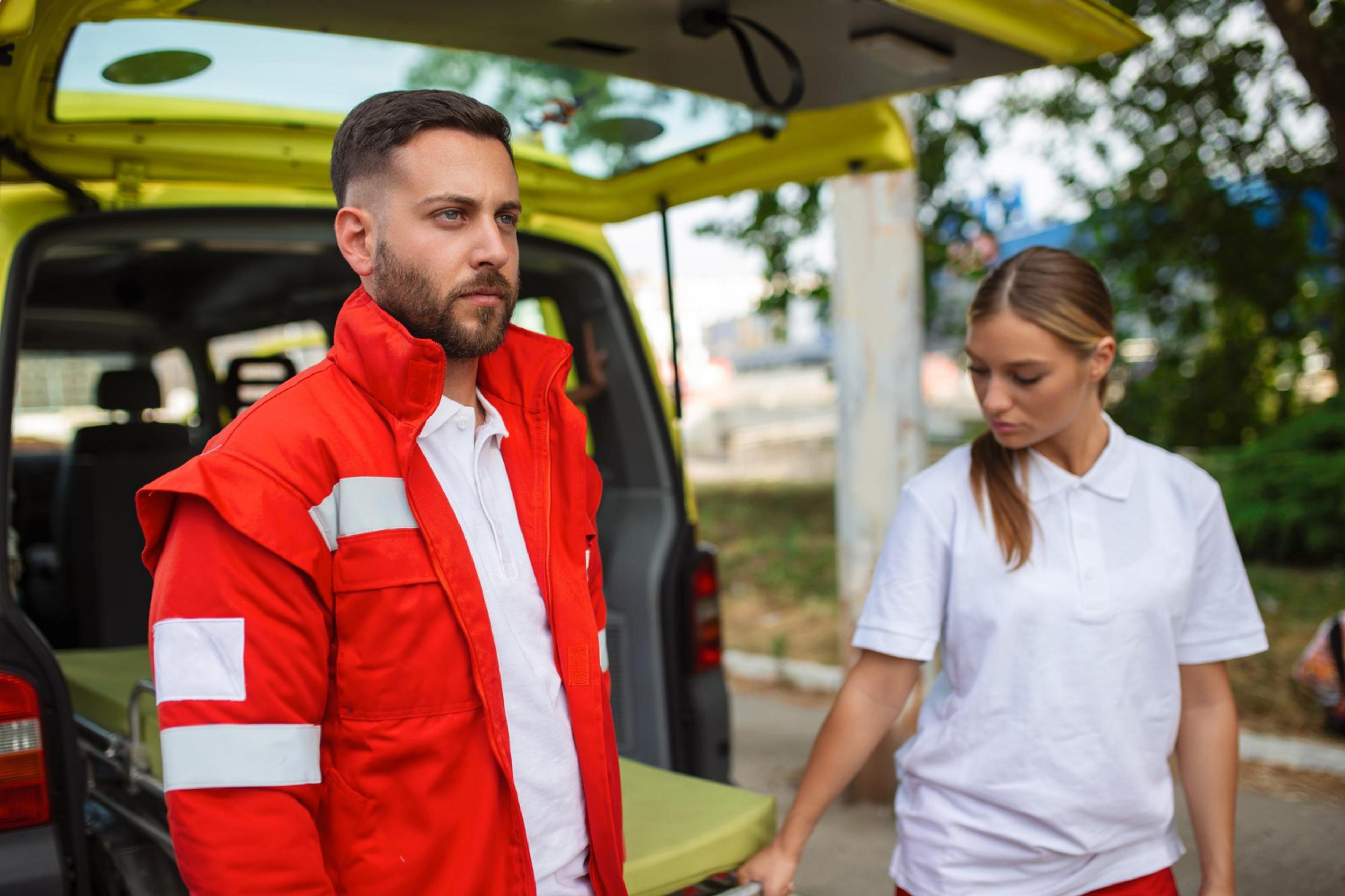 Bilde av ambulansearbeidere med en ambulansebil.