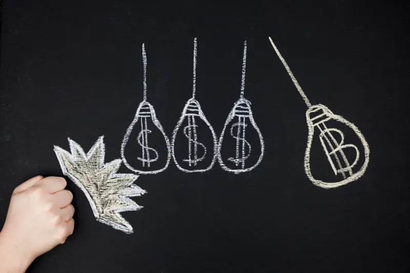 Tegning på tavle viser lyspærer med dollartegn og bitcoinsymbol som illustrerer økonomi og investering i eiendom