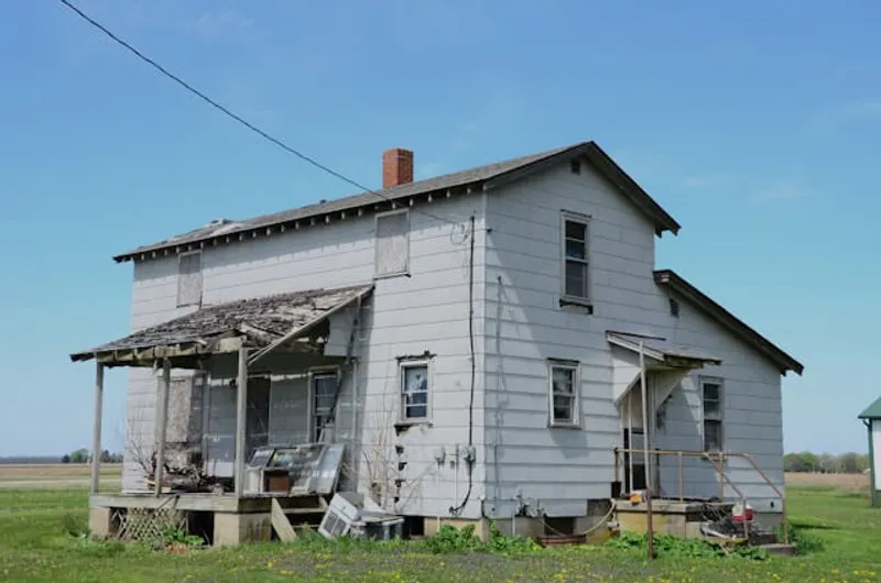 Slitt gammelt trehus med avskallet maling og ødelagt tak før oppussing