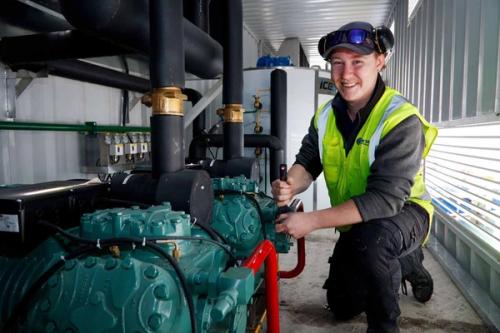 Refrigeration and air-conditioning apprentice servicing commercial refrigeration equipment in a plant room during workplace-based trainin