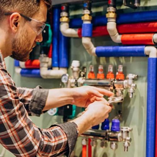 Close-up of a wrench tightening a hydraulic hose fitting on machinery