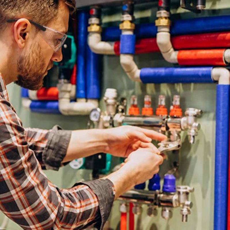 Close-up of a wrench tightening a hydraulic hose fitting on machinery