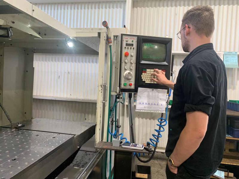 Person entering settings into a CNC machine control panel in an engineering workshop