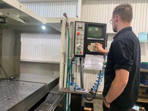 Person entering settings into a CNC machine control panel in an engineering workshop