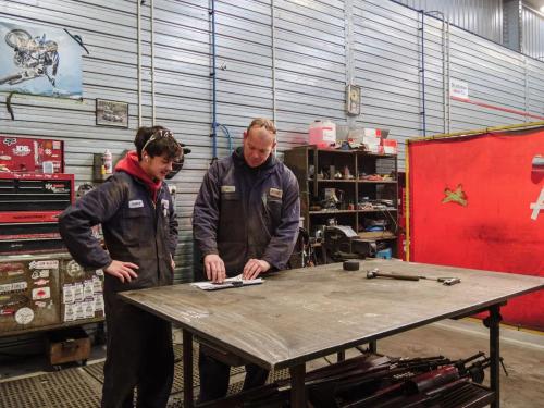 Engineer reviewing technical drawings with a supervisor in a fabrication workshop