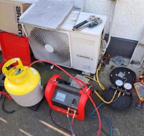 Outdoor air conditioning unit connected to a refrigerant cylinder and recovery equipment during a service job