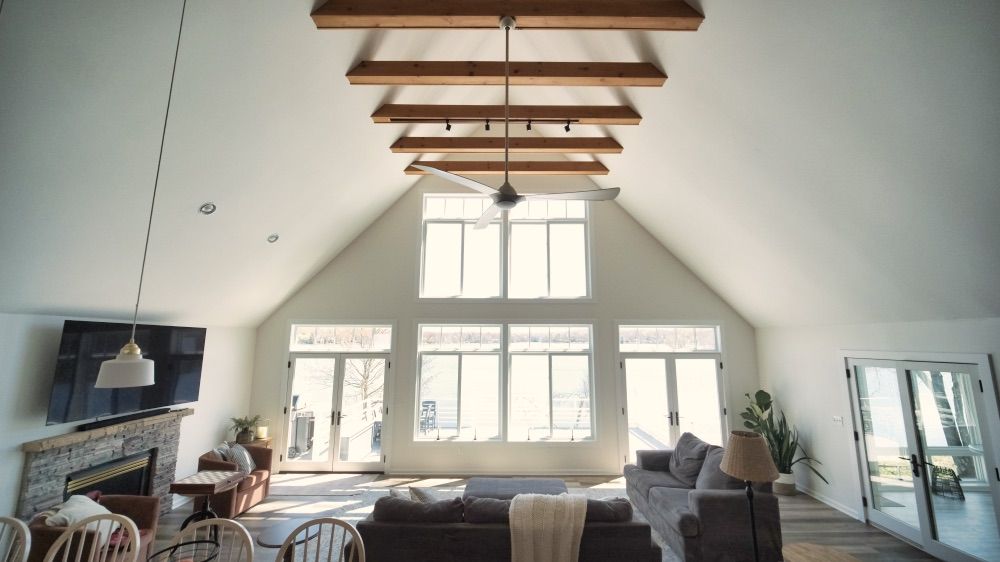 Great room with exposed beams, a fireplace, and a soaring wall of windows