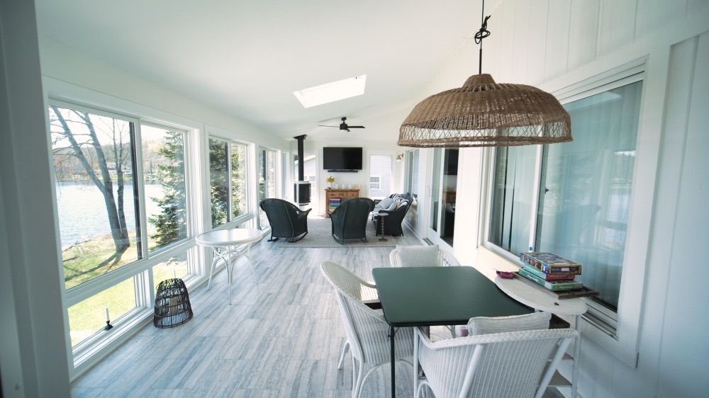 Sunroom dining space with a woven pendant light and panoramic lake views