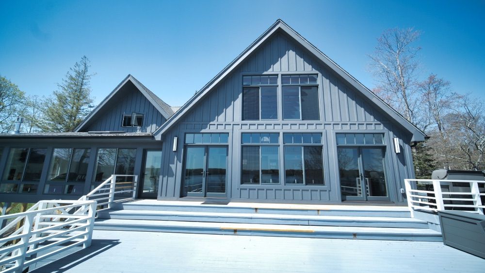 Front exterior of the renovated lake house, an A-frame design with a peaked roofline and a wall of windows