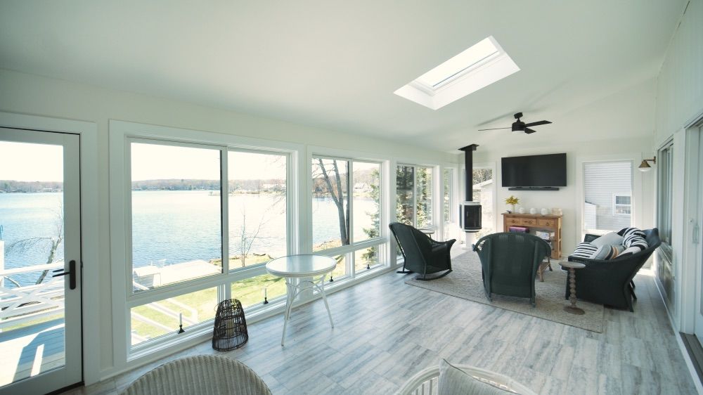 Light-filled sunroom with skylights and floor-to-ceiling windows facing the water