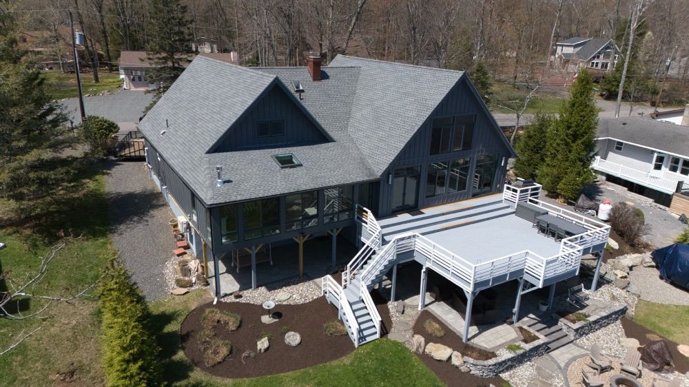 Aerial close-up of the rear of the home with white-railed decks overlooking the water
