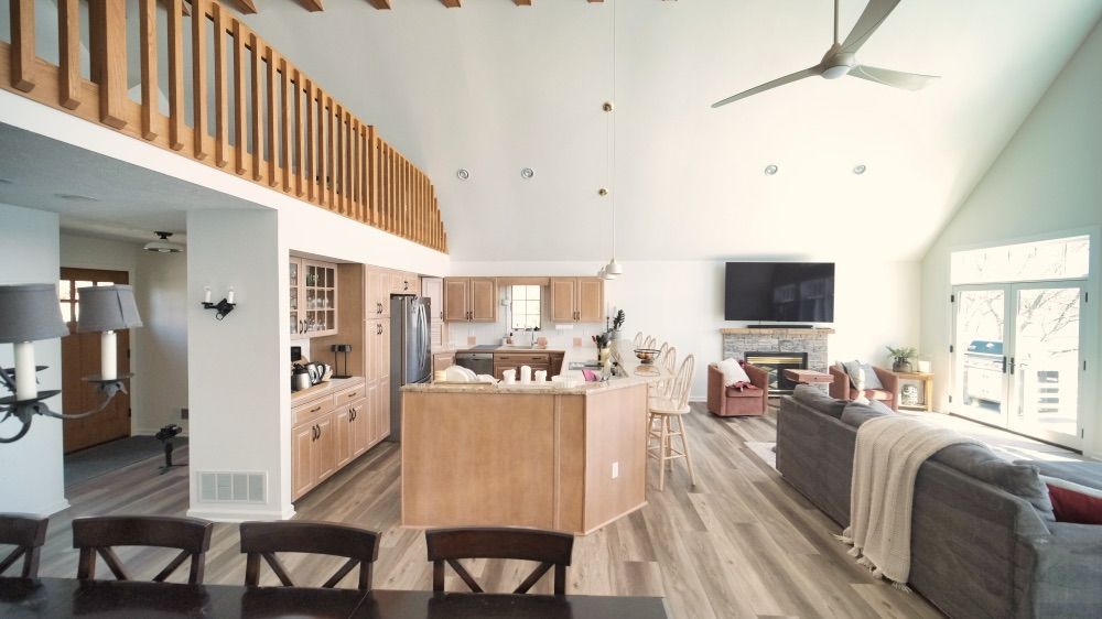 Open-concept great room with vaulted ceiling, wood-railed loft, and a remodeled kitchen