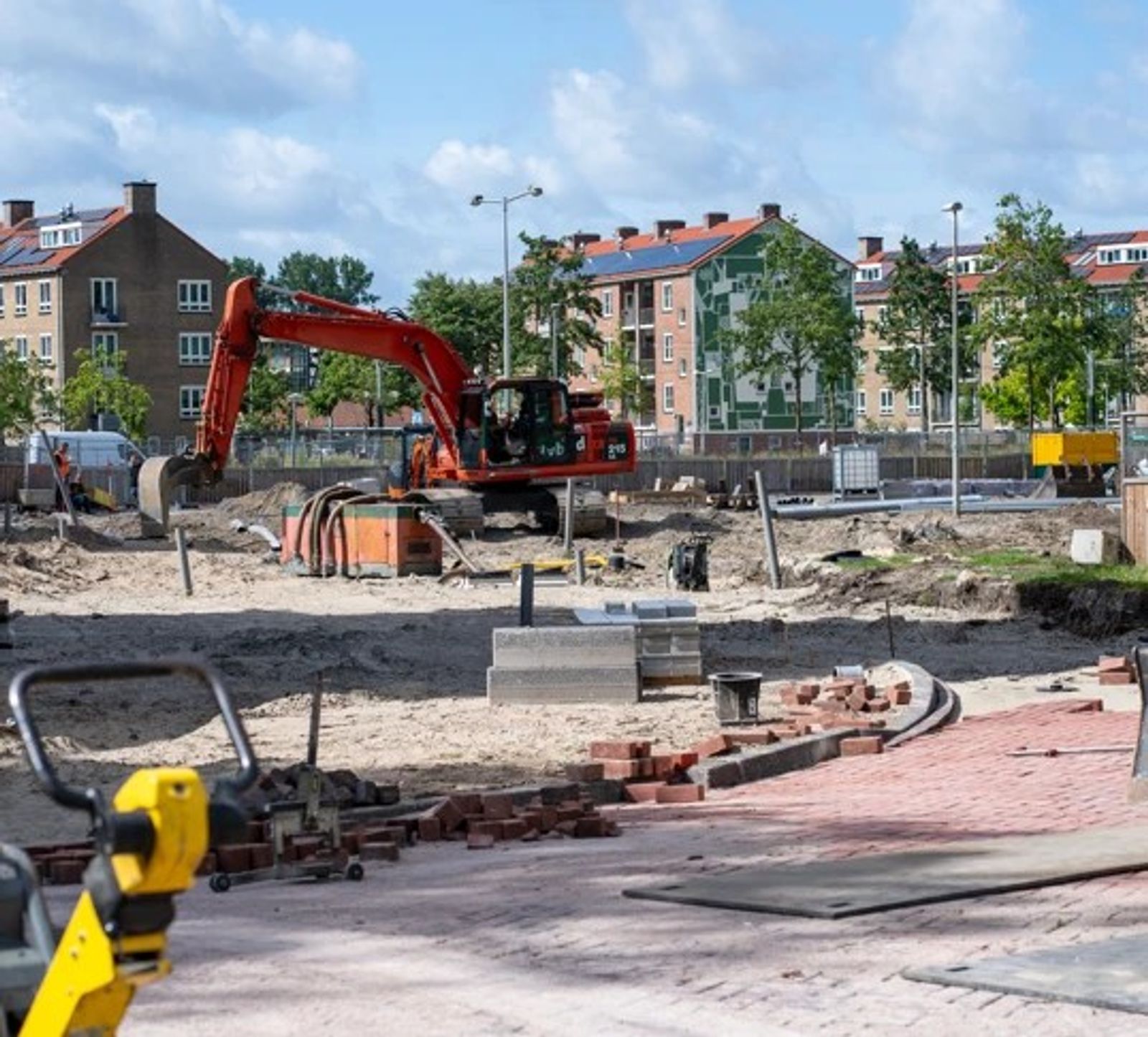 Medewerkers van Veldt Infra leggen machinaal rode klinkers met behulp van een graafmachine met legklem.