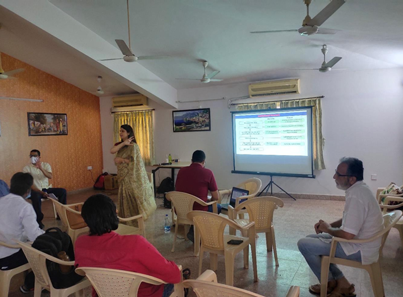 One women standing and explaining a presentation to the people sitting.