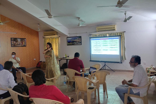 One women standing and explaining a presentation to the people sitting.
